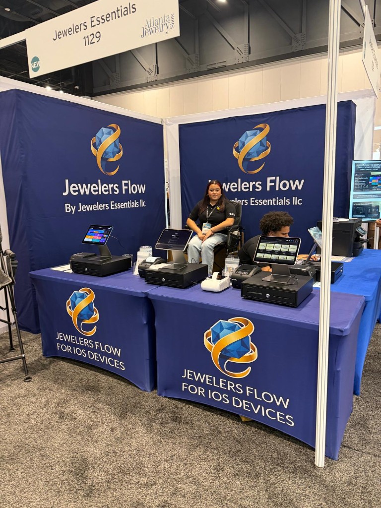 Jewelers Flow booth 1129 at Atlanta Jewelry Show Fall 2026, with iPad registers on the counter